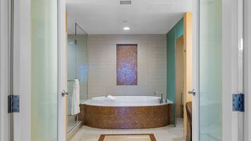 A modern bathroom with a large freestanding bathtub, a glass shower enclosure, and a decorative mosaic wall.