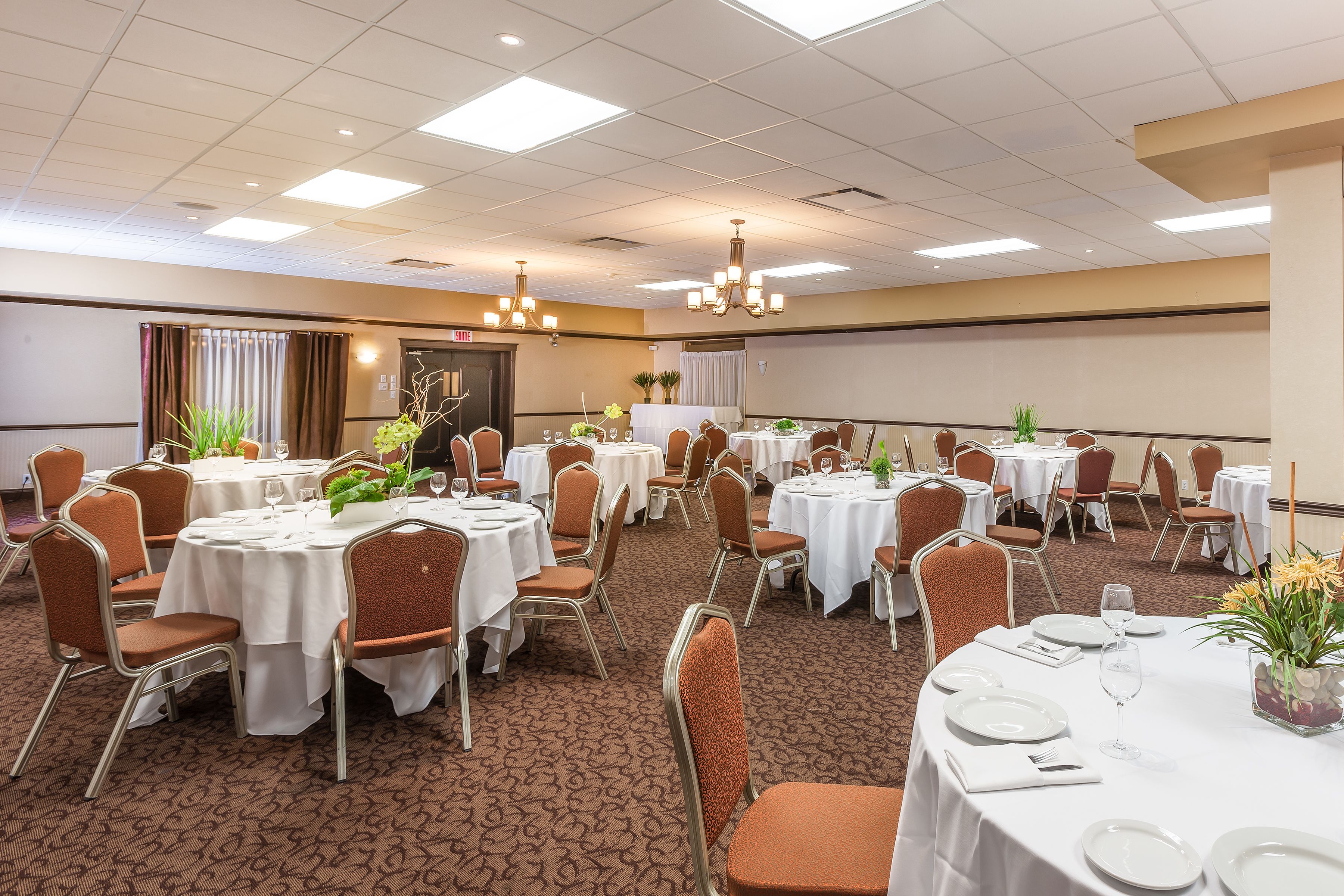 Un salón de banquetes con mesas redondas, sillas y candelabros.