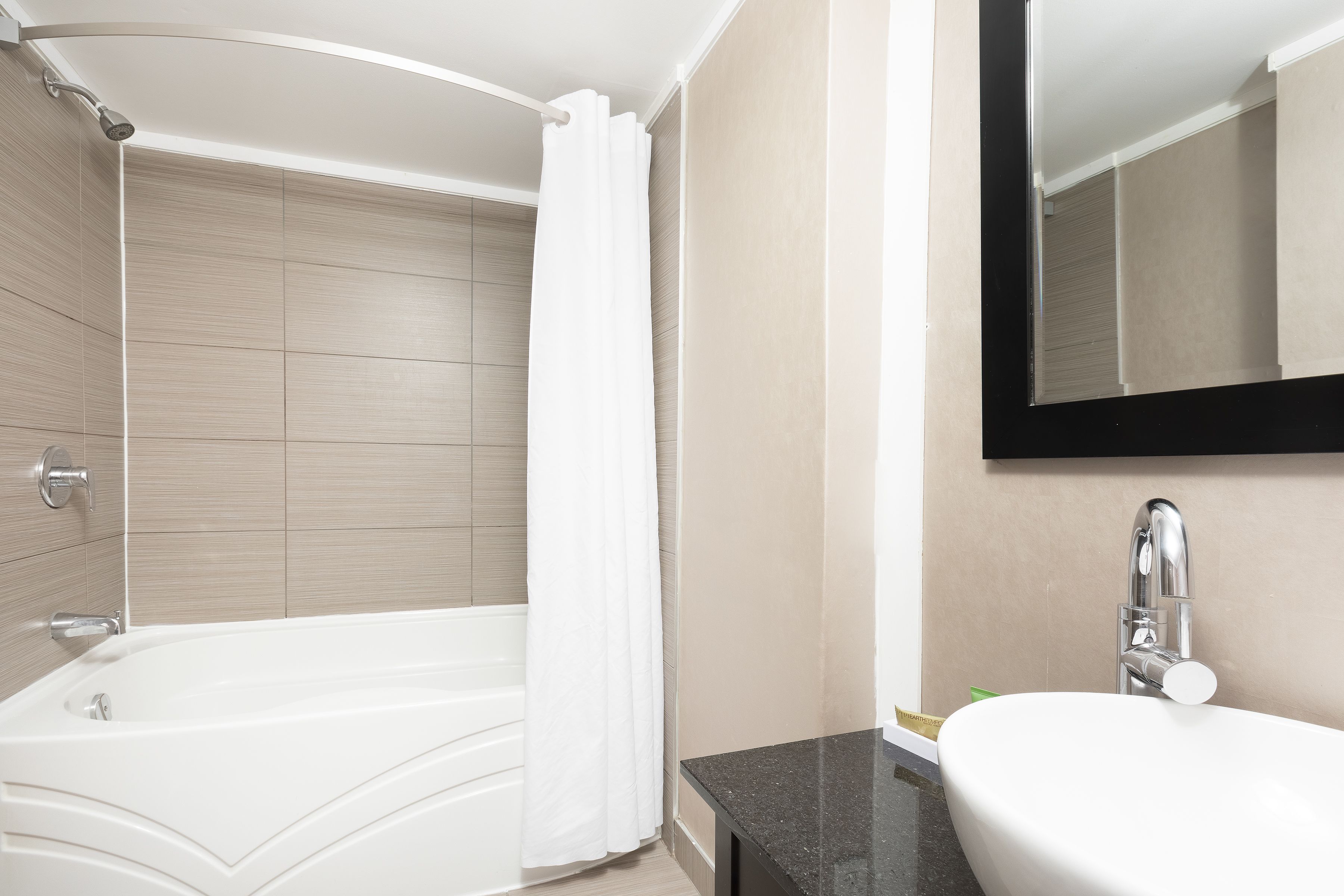 Un baño moderno con una bañera, un lavabo y un espejo.