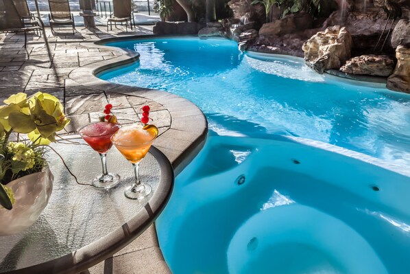 A pool area with a hot tub, two drinks on a table, and a potted plant. - Hotel Universel (Québec City)