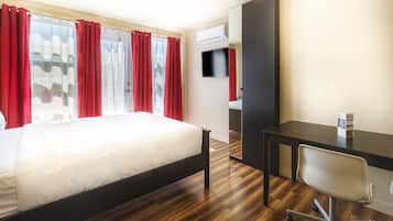 A hotel room with a bed, a desk, a chair, and a TV.