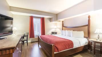 A hotel room with a bed, a desk, a TV, and a window with curtains.