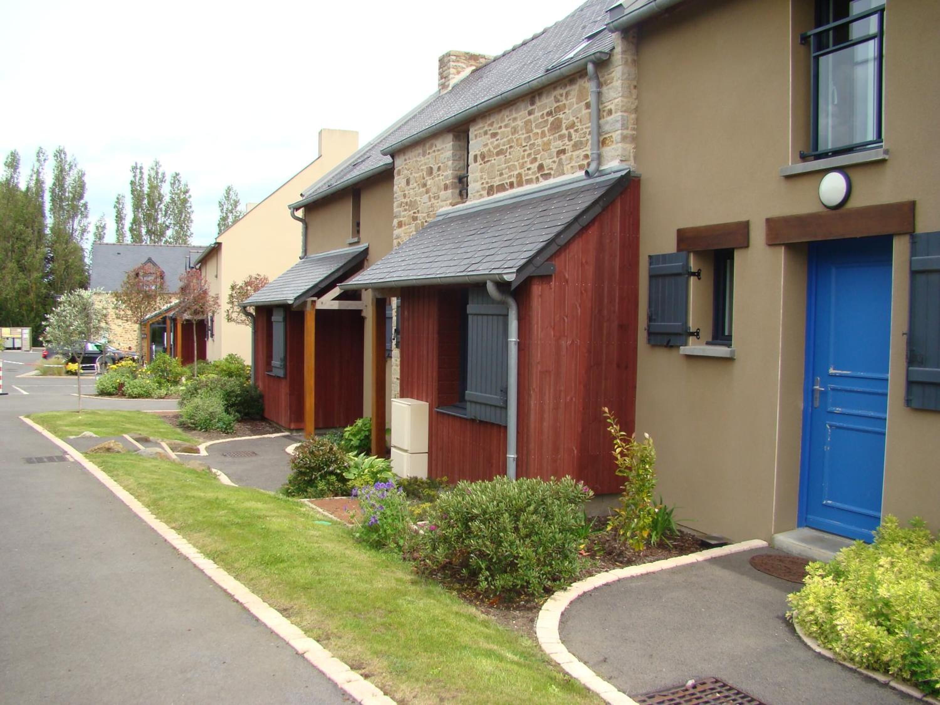 A row of townhouses with stone and wood exteriors, a blue door, and a small garden area.