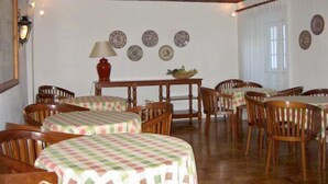 A dining area with round tables covered with checkered tablecloths, wooden chairs, and a brick ceiling. - Hotel Riviera (Évora)