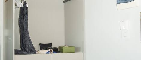 A compact room with a bunk bed, a small seating area, and a wall-mounted shelf.