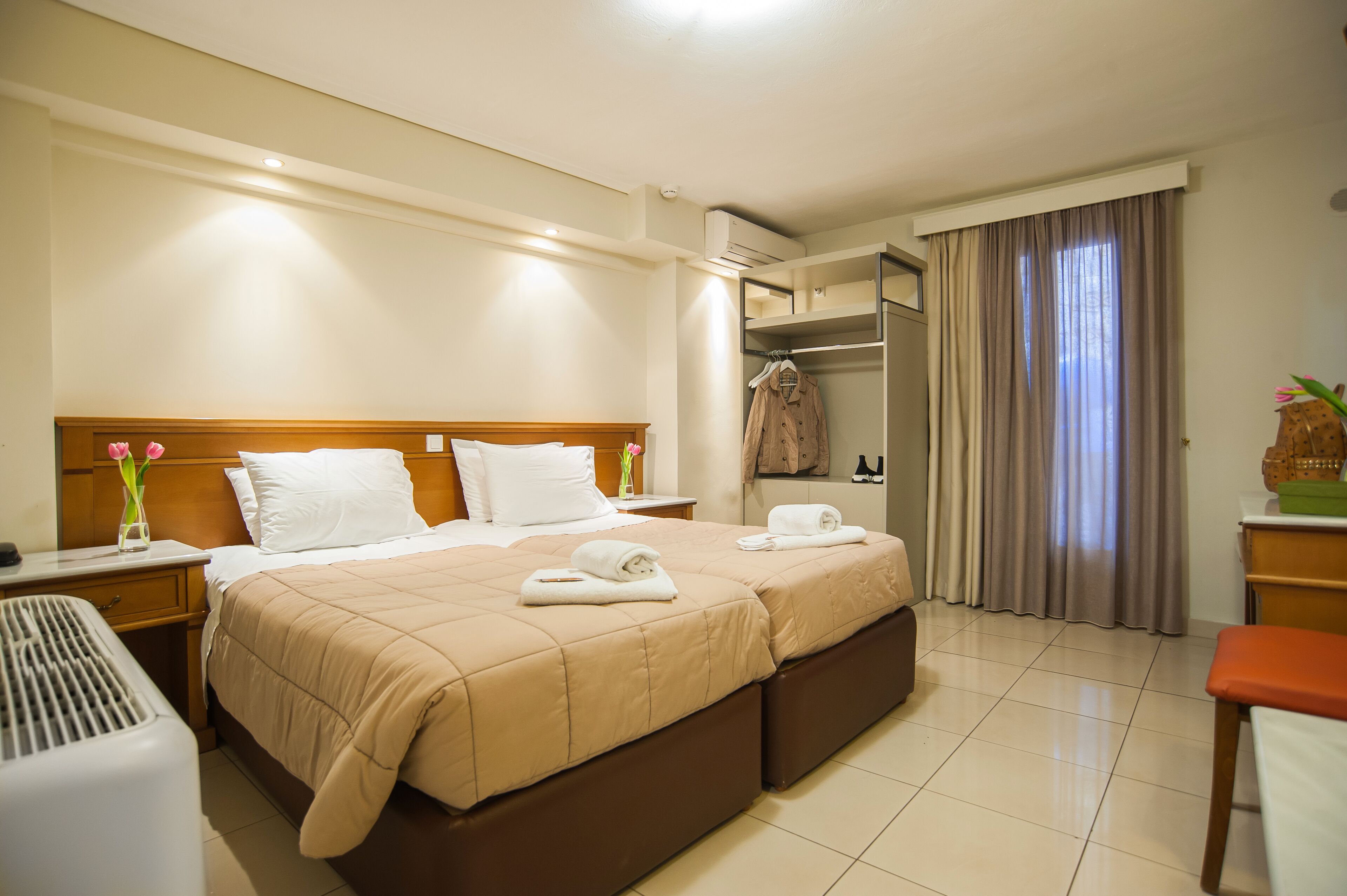Quarto de hotel com cama de casal, duas mesas de cabeceira, um guarda-roupa e zona de casa de banho.