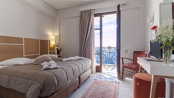 A hotel room with a bed, a desk, a chair, a TV, and a balcony with a view.