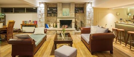 A living room with a fireplace, leather sofas, a coffee table, and a dining area with chairs and a table.
