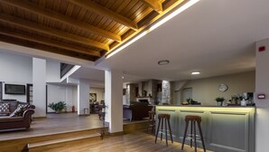 Un vaste espace de vie doté d’un plafond en bois, une cuisine avec un dosseret en pierre et un coin bar avec des tabourets.