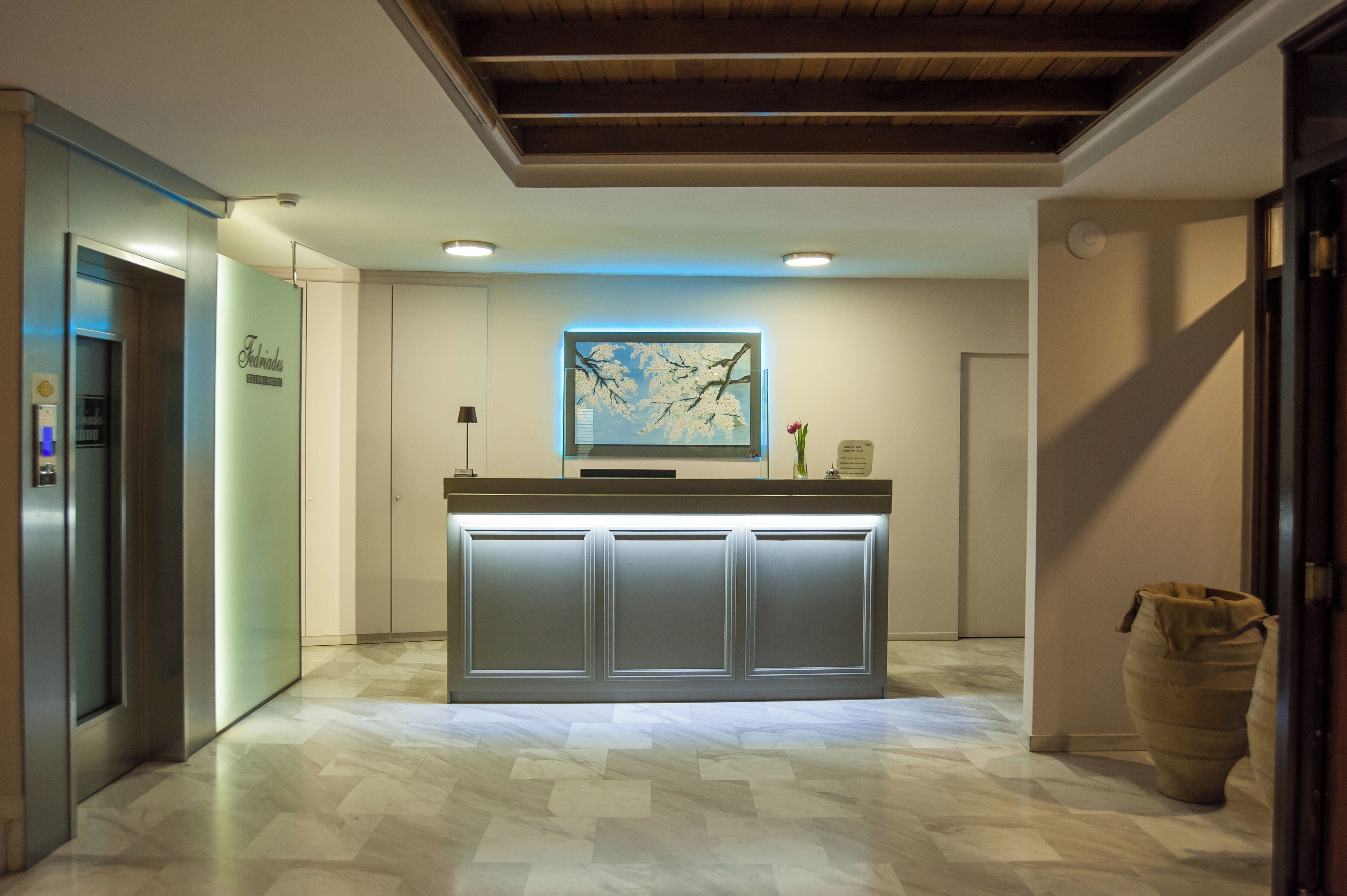 A reception area with a modern design, featuring a reception desk, a large framed artwork on the wall, and a large vase on the right.