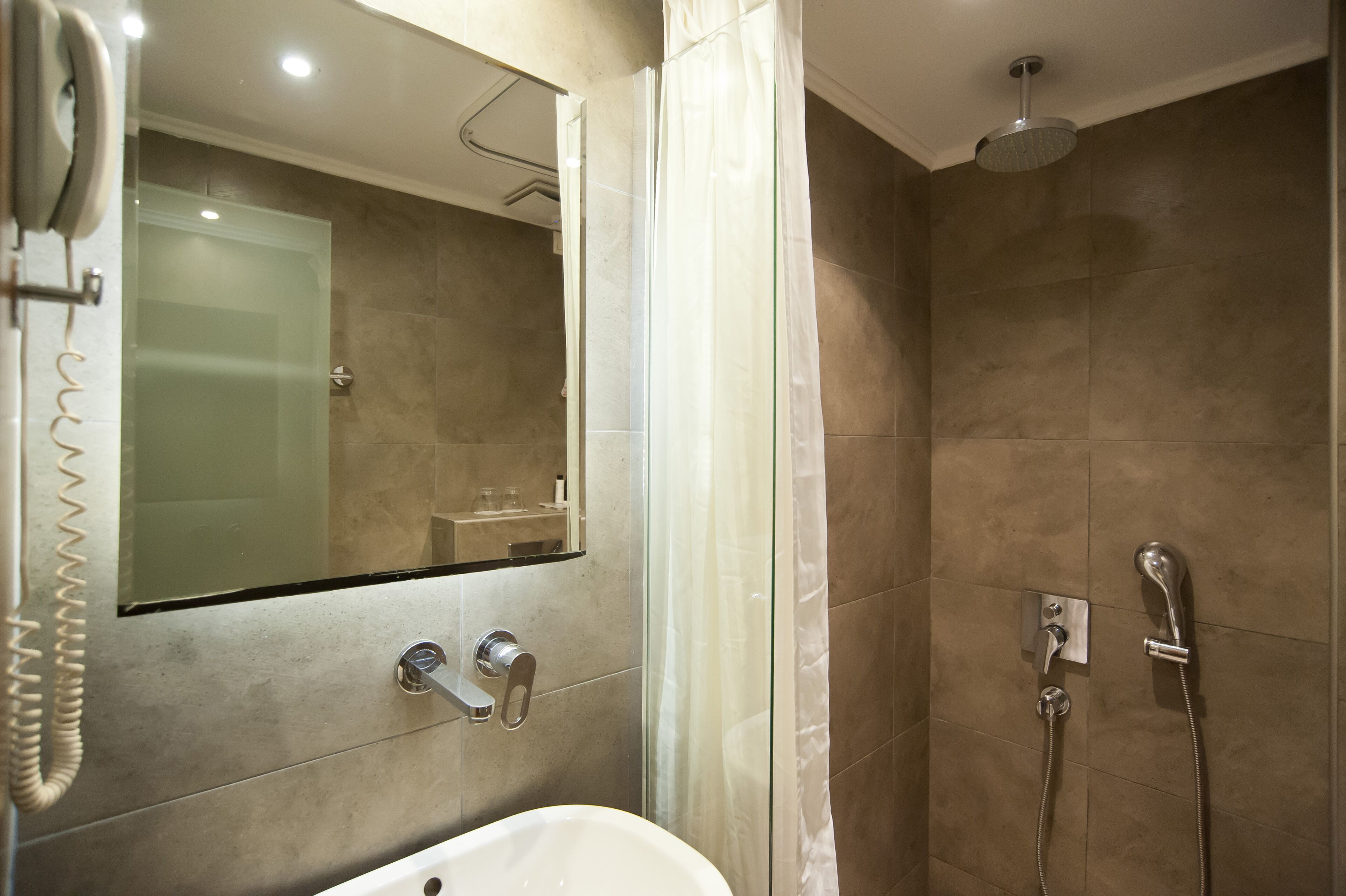Une salle de bain moderne avec une douche à parois de verre, un lavabo encastré et un miroir au-dessus du lavabo.