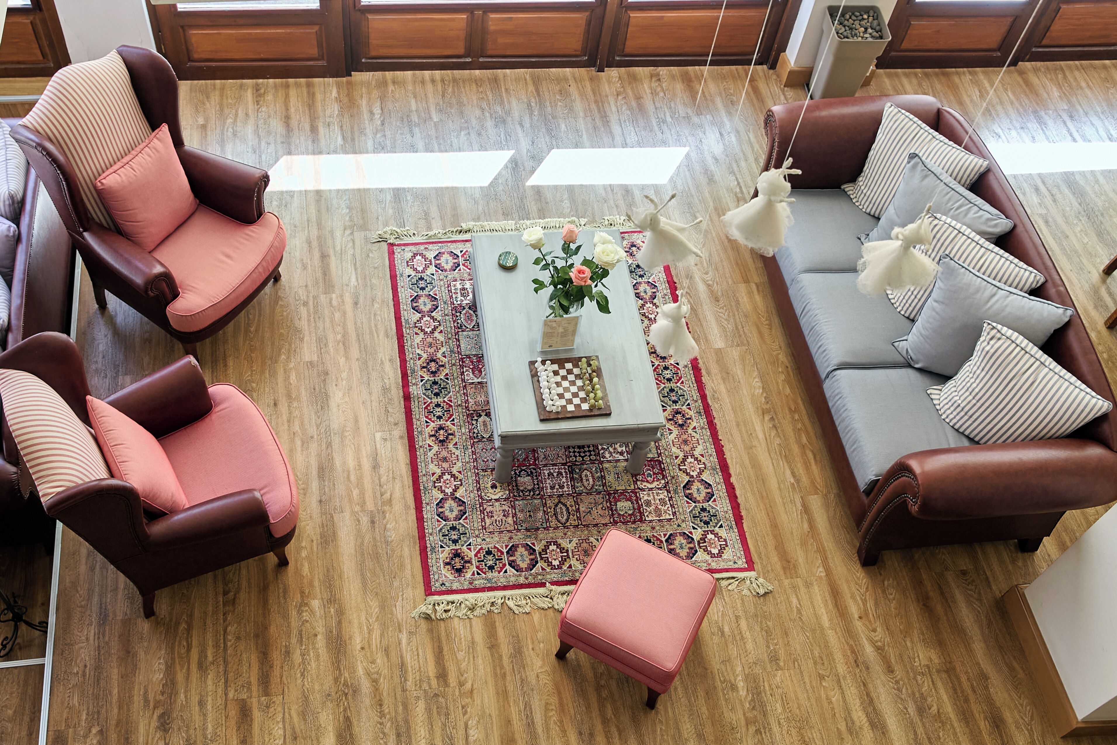 A room with a brown leather sofa, a matching armchair, a small coffee table with a vase of flowers, and a patterned rug.