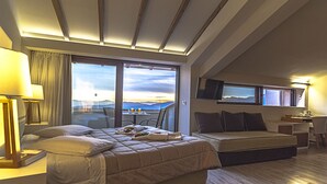 Une chambre d’hôtel avec un lit, un bureau, une chaise, une télévision et une vue sur les montagnes.