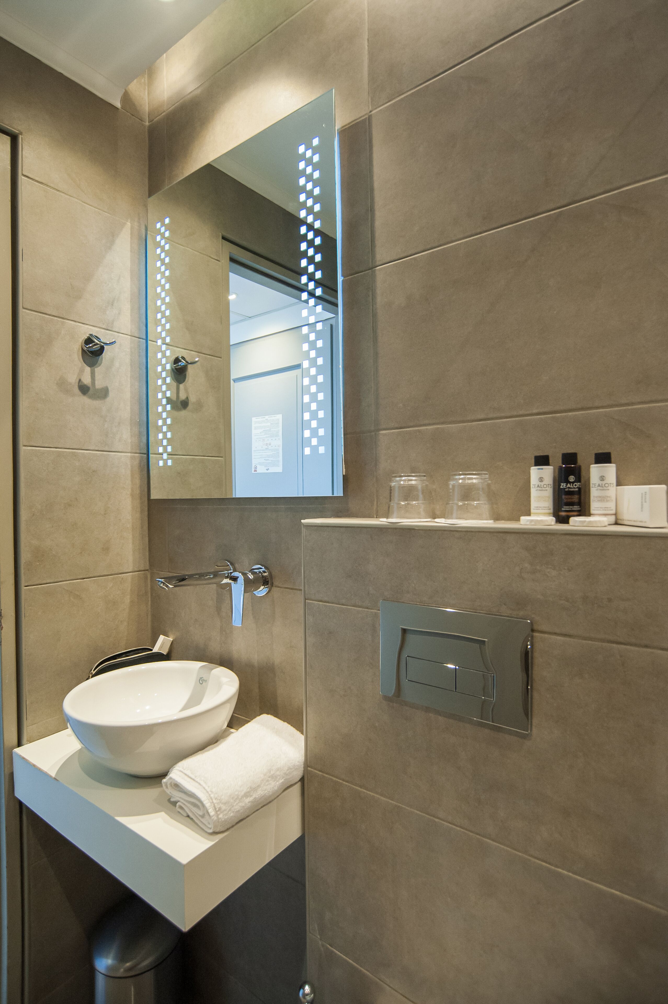 A modern bathroom with a large mirror, a white sink, and a towel rack.