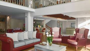 A spacious living area with a high ceiling, a staircase, and a balcony.