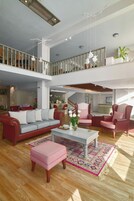 A spacious living area with a high ceiling, a staircase, and a balcony.