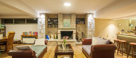 A living room with a fireplace, sofas, a coffee table, and a bar area.