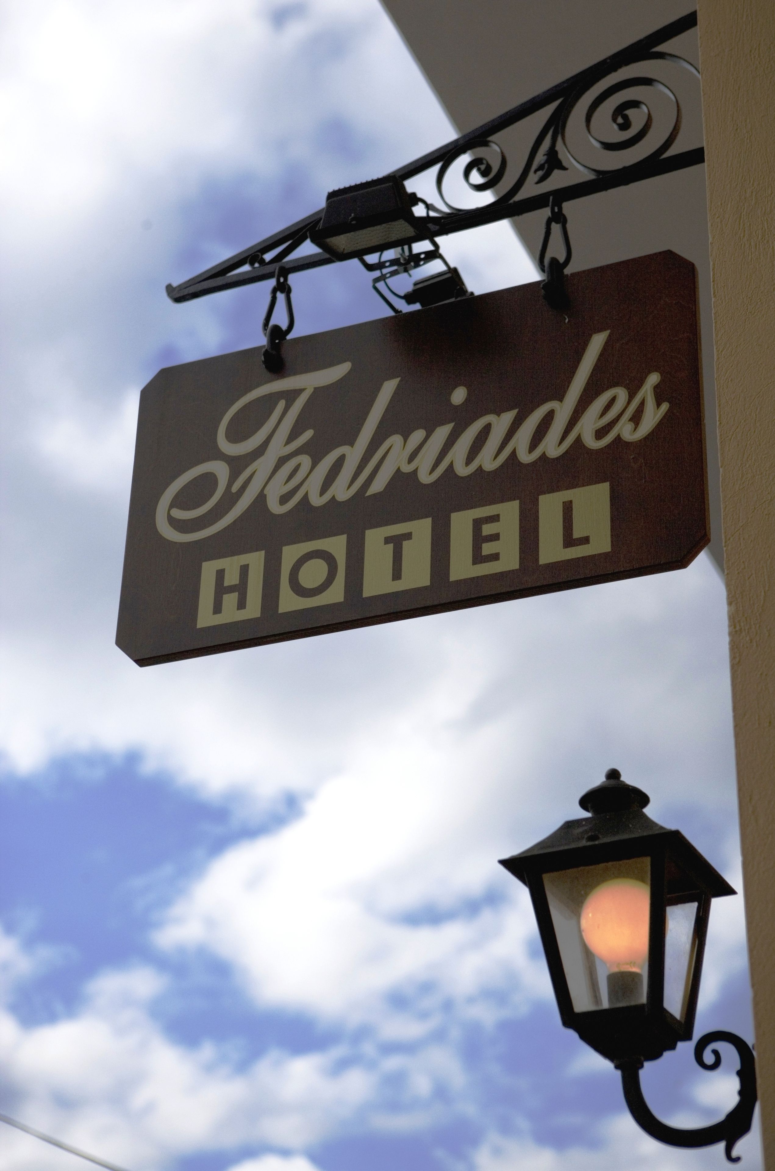 A hotel sign with the name "Fedriades Hotel" against a cloudy sky.