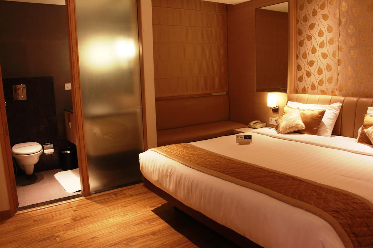 A hotel room with a bed, bedside table, and a bathroom with a toilet and sink.