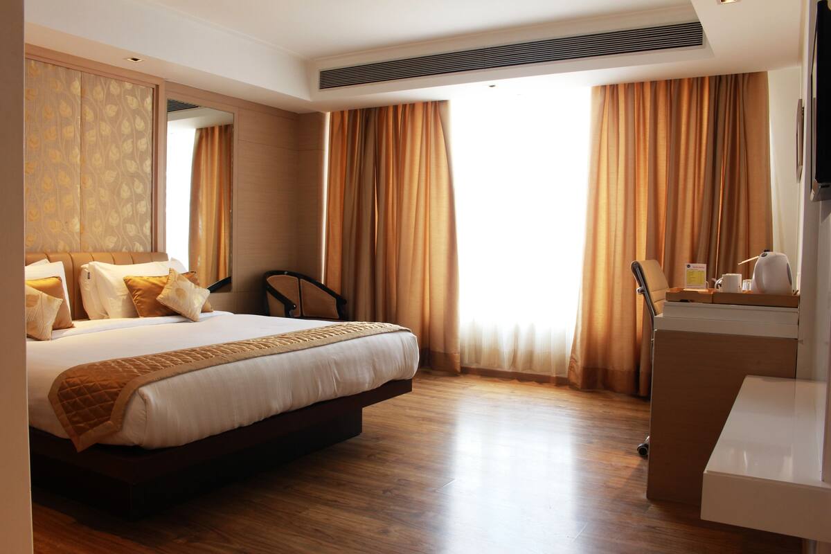 A hotel room with a large bed, a desk, and a chair.
