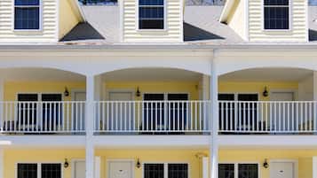 A three-story building with a yellow exterior, white trim, and a balcony on each floor.