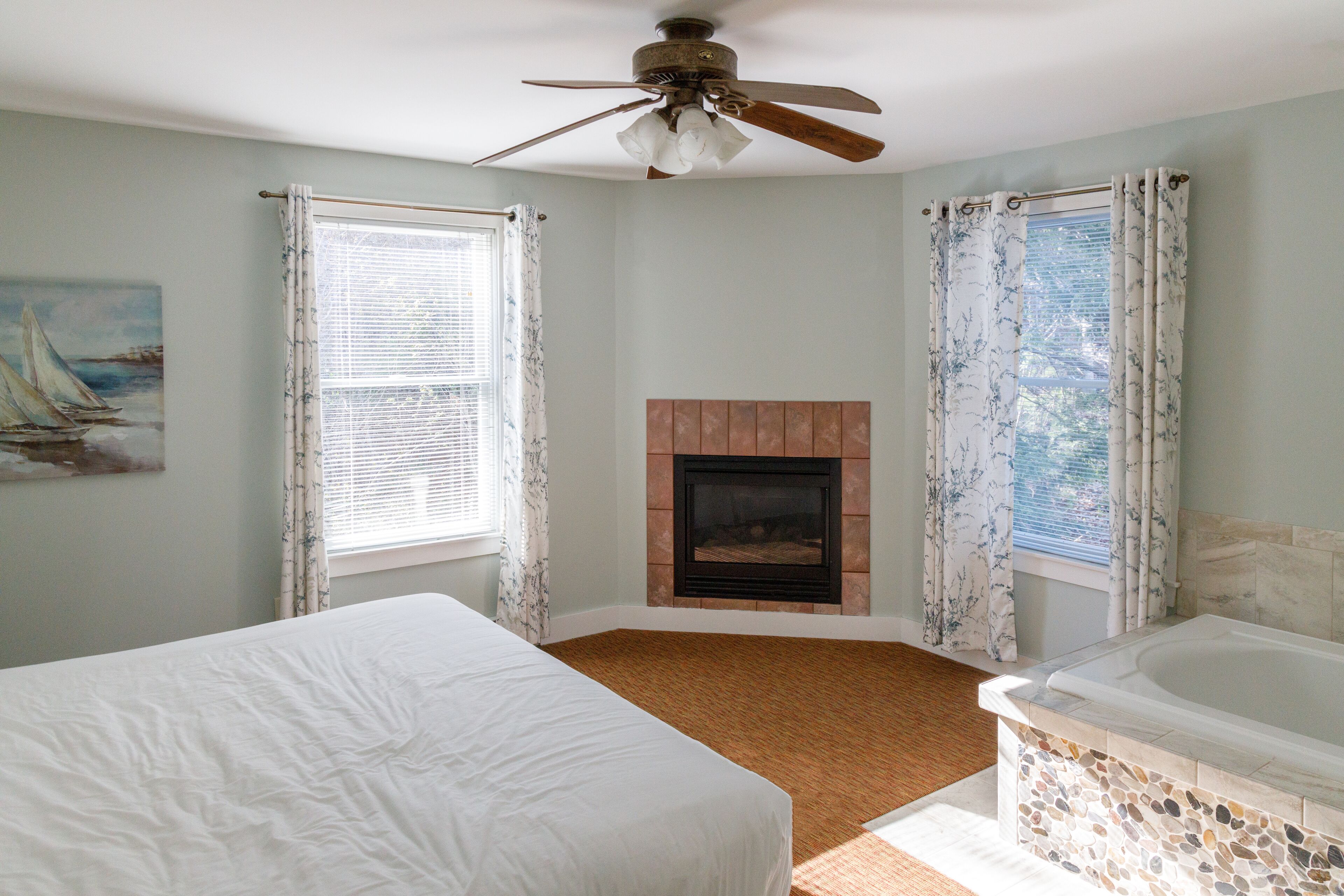 A bedroom with a bed, a fireplace, and a bathtub.