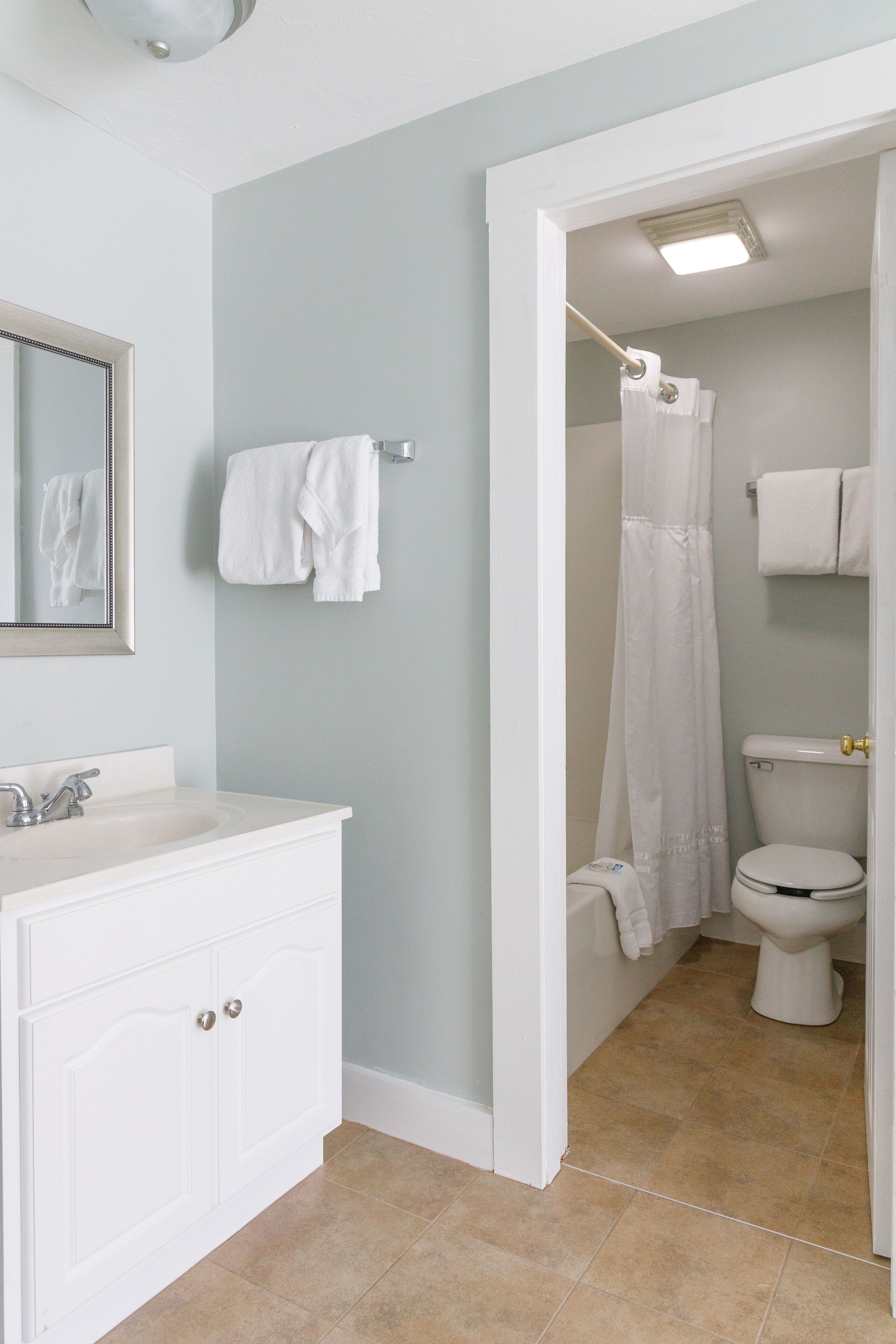 Une salle de bain avec un meuble-lavabo blanc, des toilettes et un espace douche.