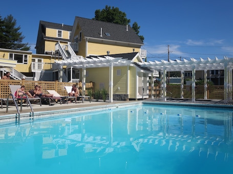 Una piscina al aire libre de temporada, sombrillas