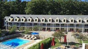 A hotel with a pool area, multiple balconies, and a row of rooms with a consistent architectural style. - The Admiral's Inn Resort (Ogunquit)