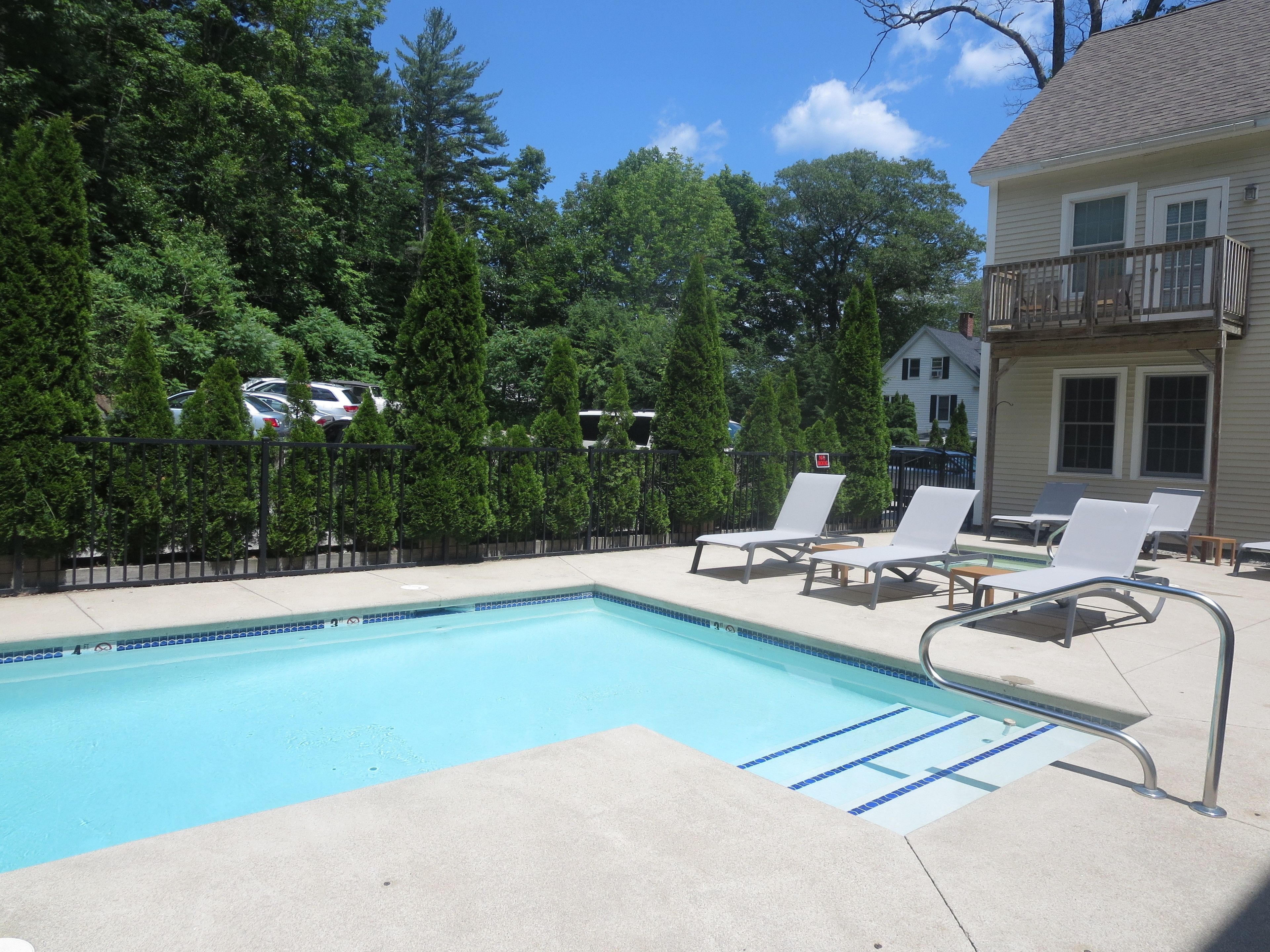 A swimming pool with lounge chairs and a wooden deck.