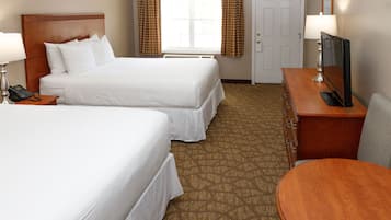 Ein Hotelzimmer mit zwei Betten, einem Schreibtisch, einem Fernseher, einem Telefon und einer Tür.
