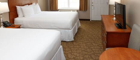 A hotel room with two beds, a desk with a TV, a telephone, and a door.