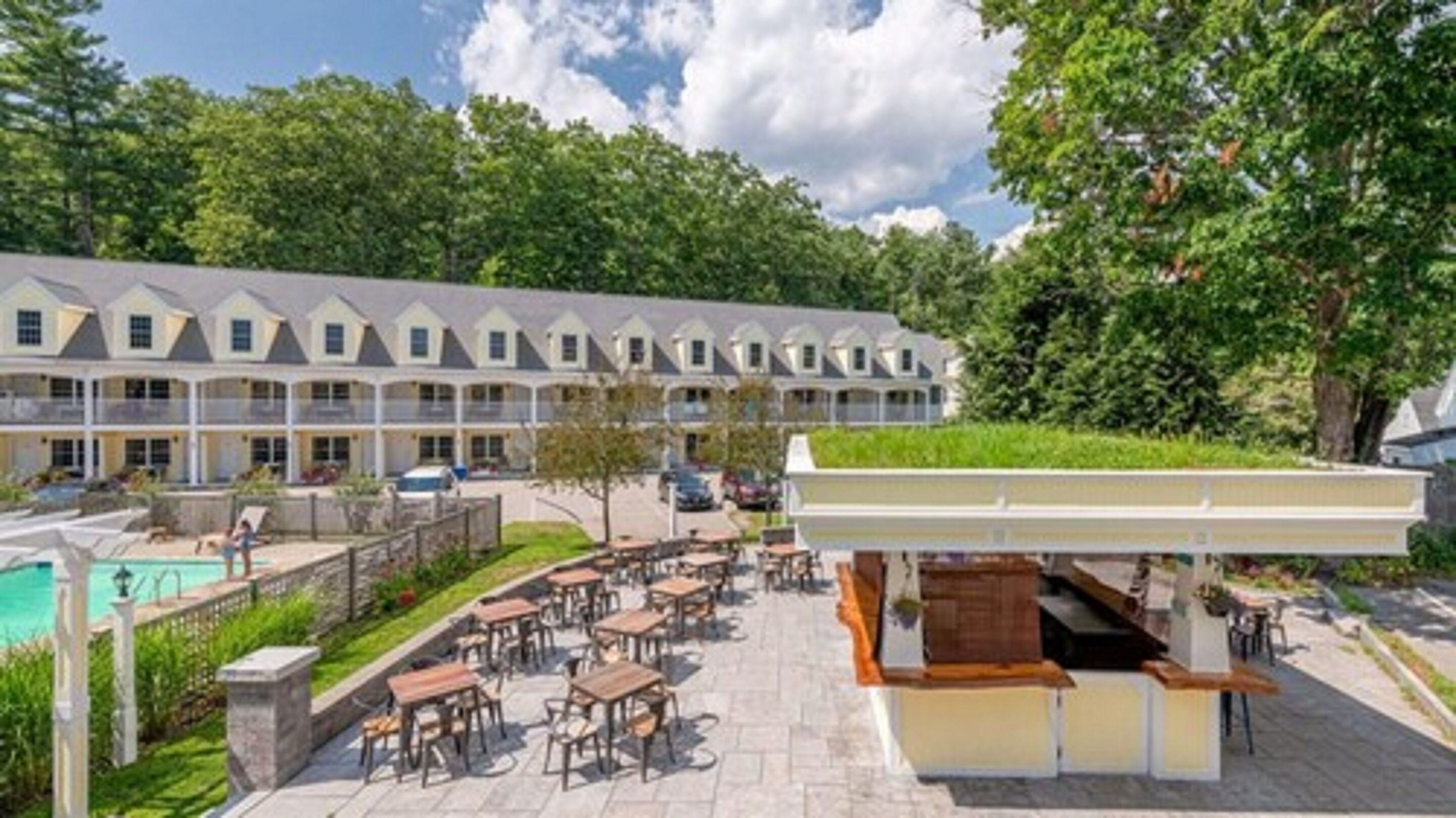 Un hotel con piscina, zona de estar exterior y espacio cubierto.