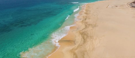 En privat strand, hvidt sand, liggestole, parasoller