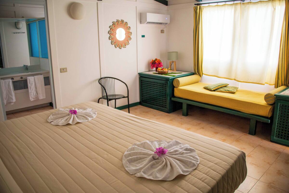 Een hotelkamer met twee bedden, een spiegel, een wastafel en een raam met gordijnen.