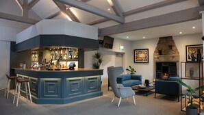 Eine moderne Bar mit gebogener Theke, Barhocker und einer Lounge-Ecke mit Sofas und einem Couchtisch.