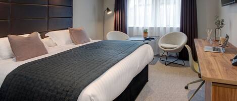 Una habitación de hotel moderna con una cama grande, un escritorio y una silla.