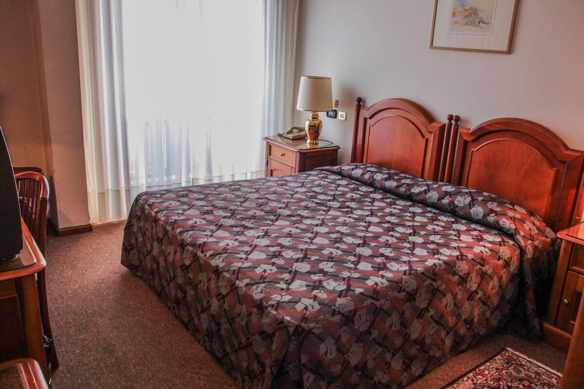 Une chambre d’hôtel avec un grand lit, une table de chevet avec une lampe, une chaise et un bureau.