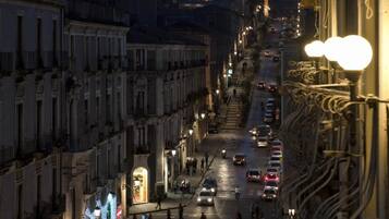 Straßenansicht im Abenddämmerung mit Gebäuden an beiden Seiten, Autos auf der Straße und Straßenlaternen.