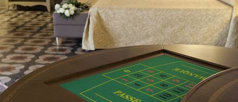 Una mesa de dados en una habitación de hotel, con una cama al fondo.