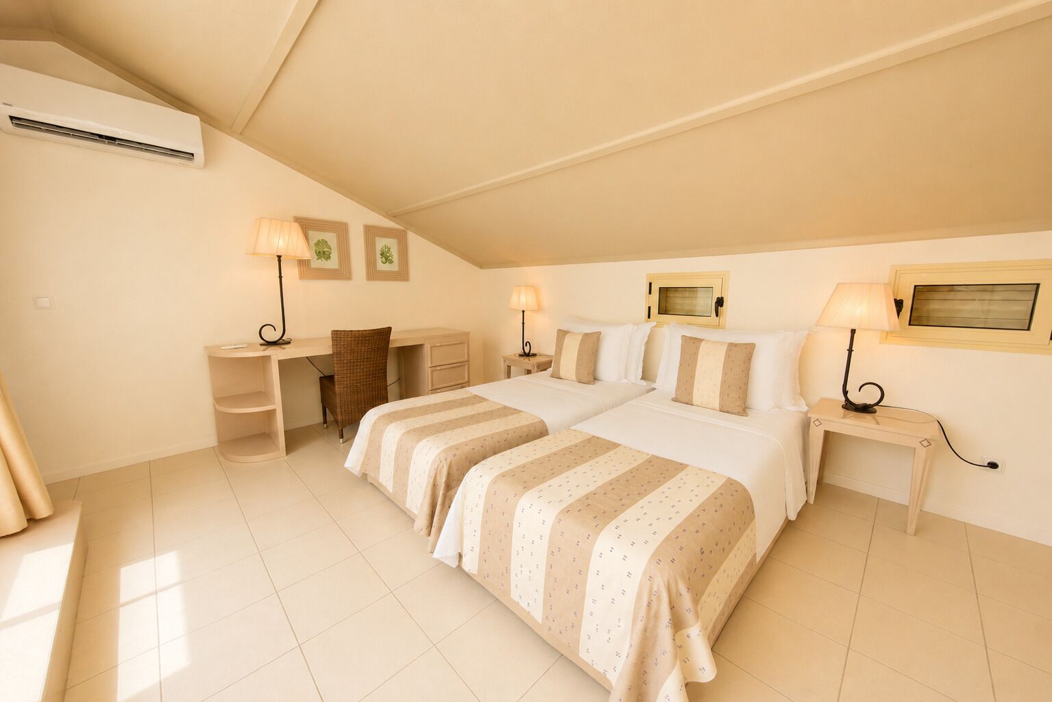 Een hotelkamer met twee bedden, een bureau, een stoel en een raam.