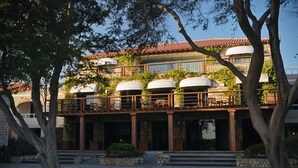 A hotel with a stone facade, multiple balconies, and a courtyard with trees.