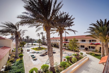 A courtyard with palm trees, outdoor seating, and a pool.