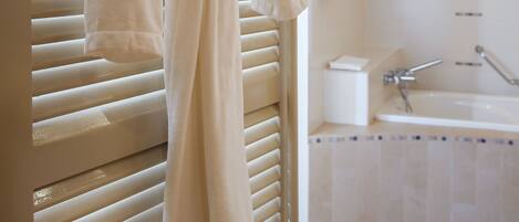 A bathroom with a bathtub, a towel rack with a robe, and a toilet.
