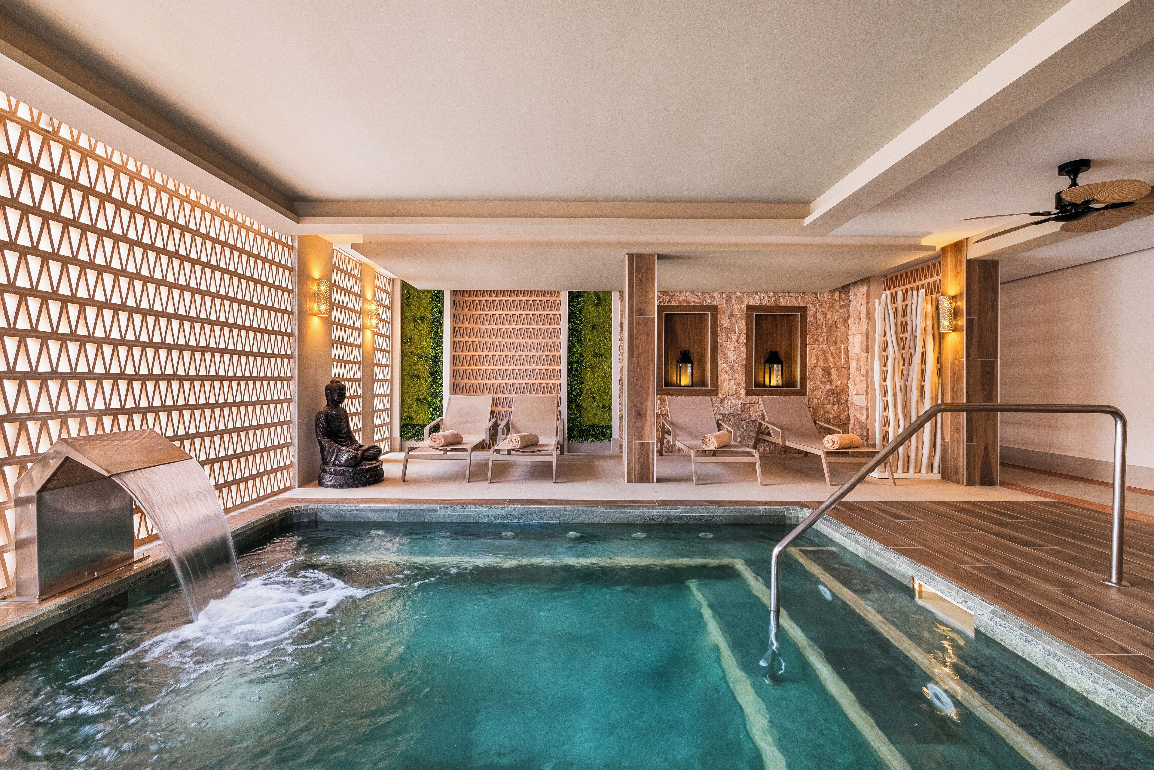 Un área de spa con hidromasaje, asientos y una cascada.