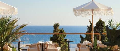 A terrace with wicker furniture, a round table, and a view of the sea.