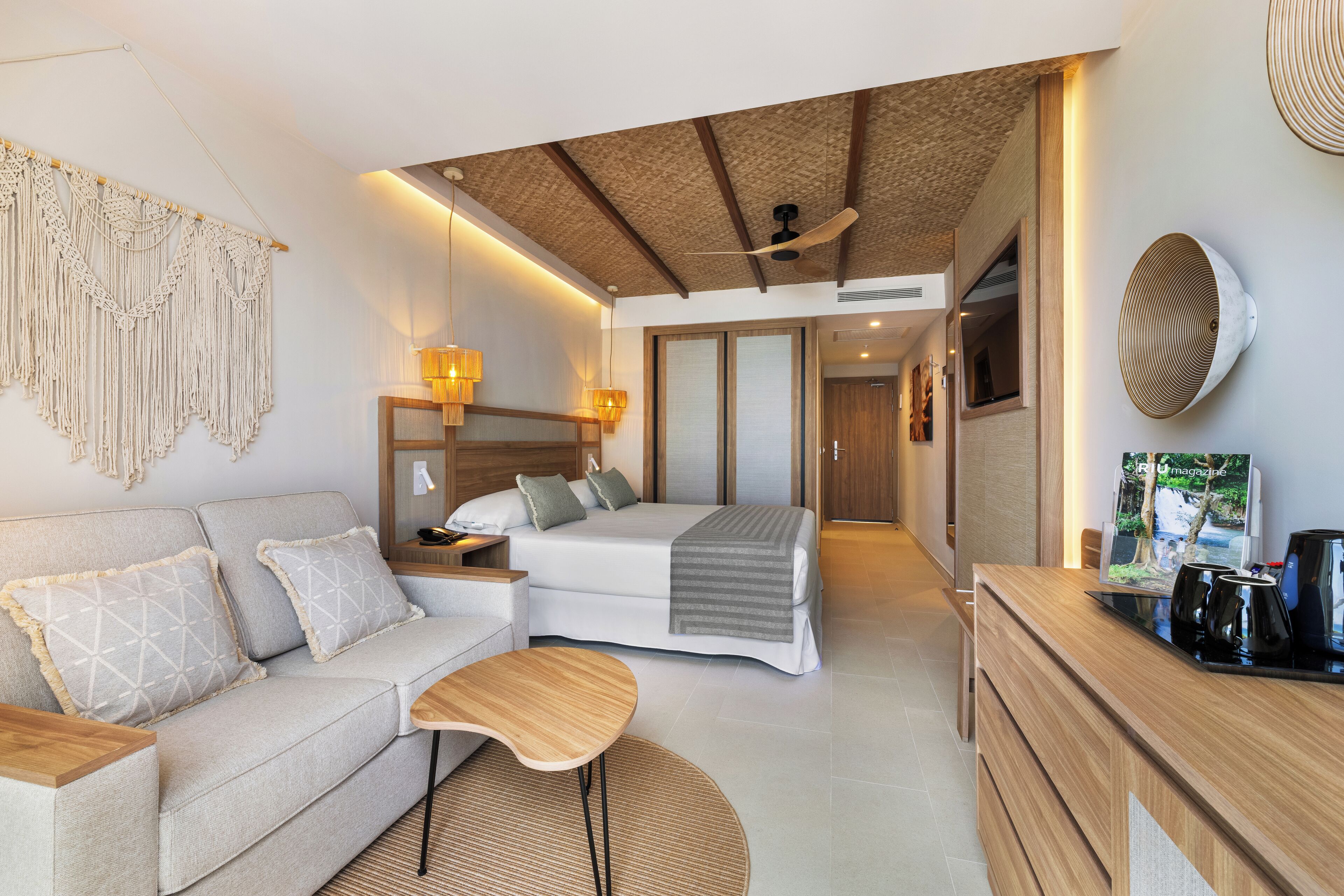 Une chambre d’hôtel moderne équipée d’un canapé, d’un lit, d’un bureau en bois et d’un ventilateur de plafond.