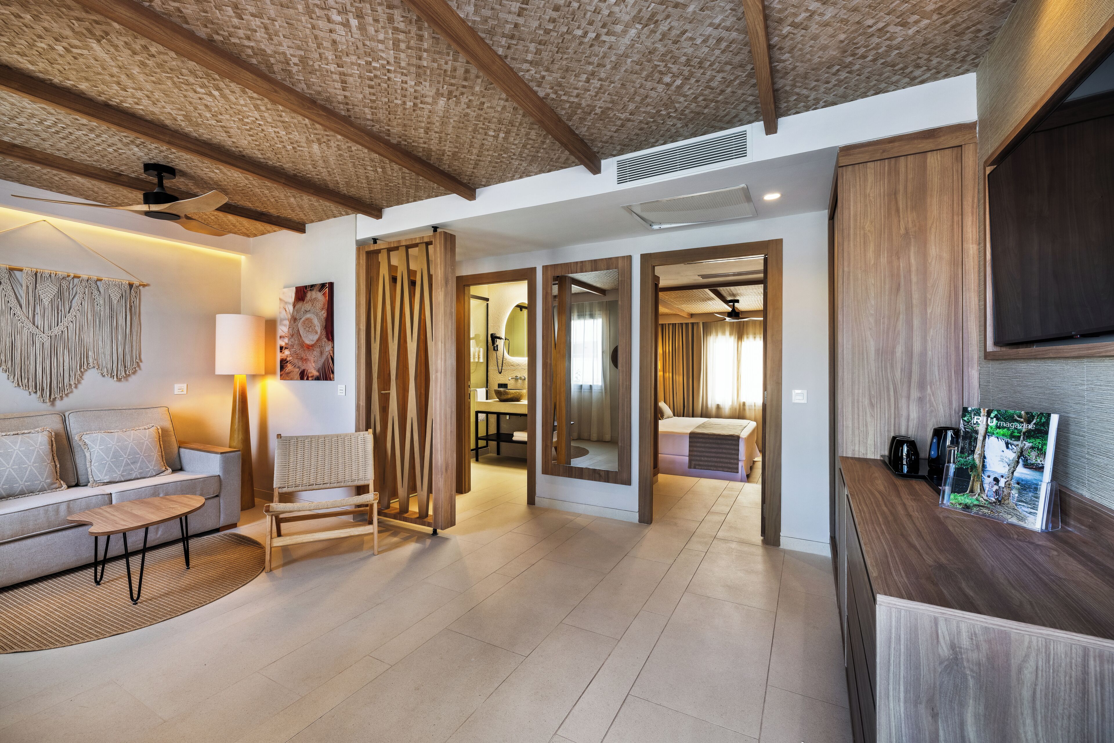 A modern hotel lobby with a sofa, a coffee machine, and a wooden reception desk.