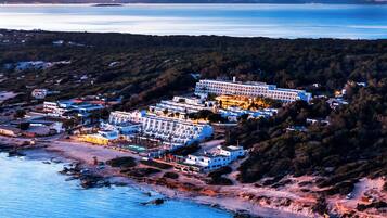 A coastal hotel with multiple buildings, a beach, and a view of the sea.