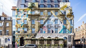 Ein mehrstöckiges Gebäude mit einer farbenfrohen Fassade, großen Fenstern und einem schwarzen Auto vor der Tür.